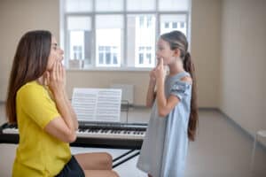 Girl in blue dress and her teacher doing voice exercises Voice Lessons in Lexington, MA