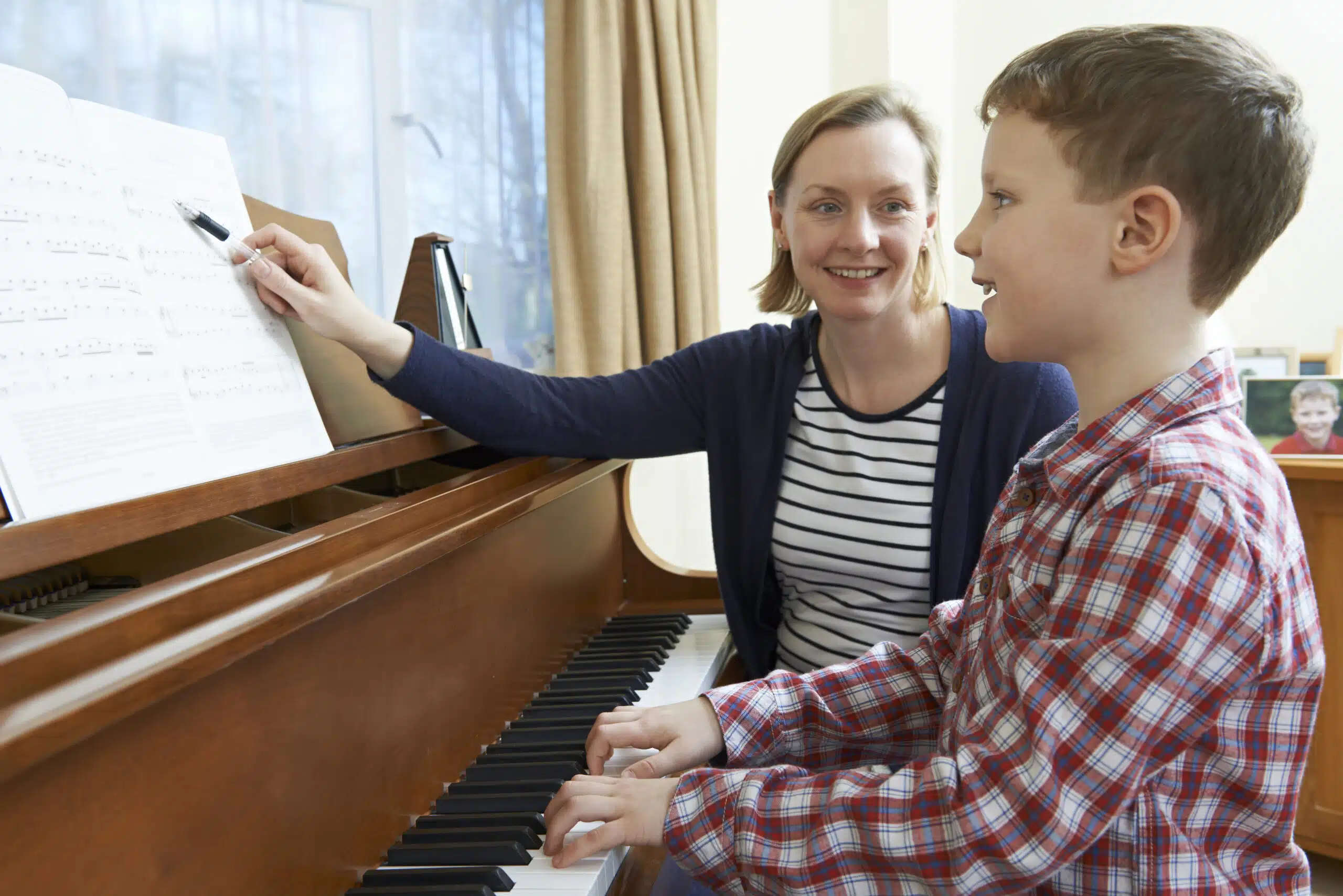 Child learning piano with a caring teacher