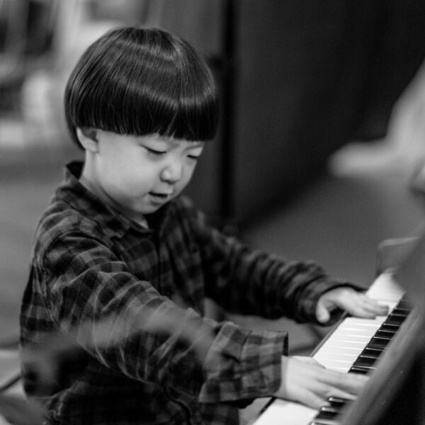A young child playing hard on a piano.